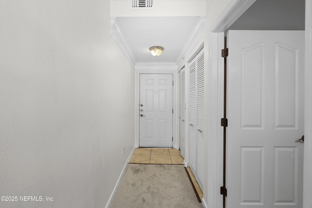 hallway with visible vents, baseboards, crown molding, and light colored carpet