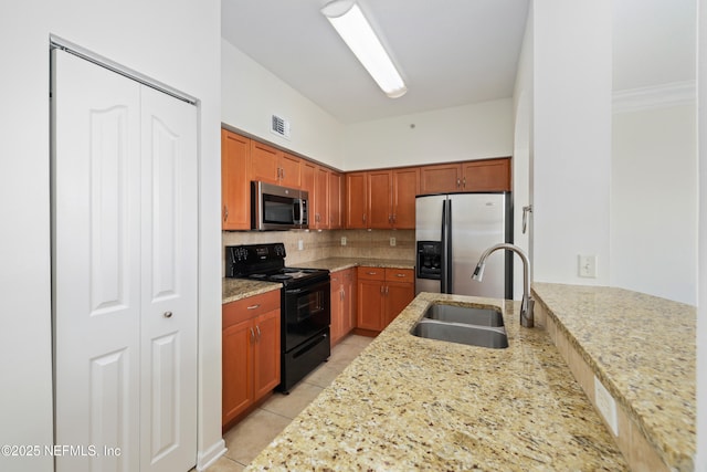 kitchen featuring stainless steel appliances, light stone countertops, decorative backsplash, and a sink