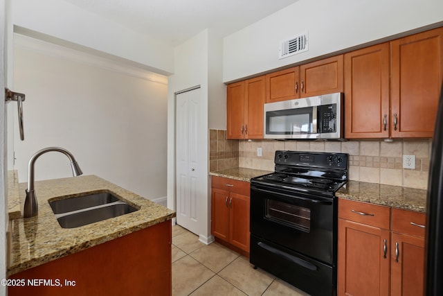 kitchen featuring visible vents, decorative backsplash, stainless steel microwave, black range with electric stovetop, and a sink