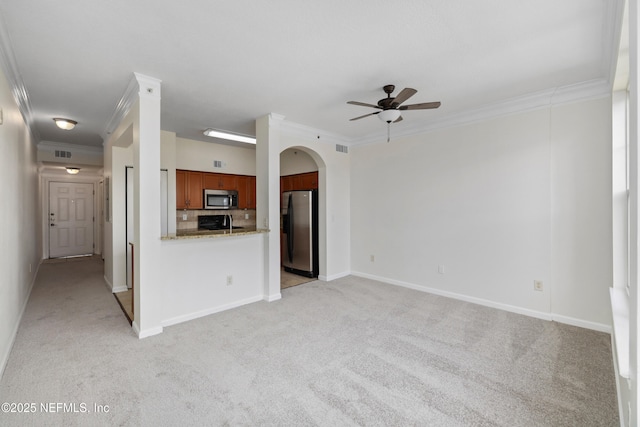 unfurnished living room with crown molding, arched walkways, ceiling fan, and light carpet