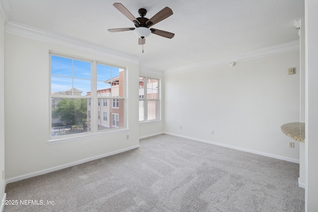 spare room featuring crown molding, baseboards, ceiling fan, and carpet flooring