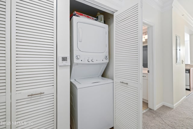washroom featuring laundry area, ornamental molding, light carpet, baseboards, and stacked washing maching and dryer