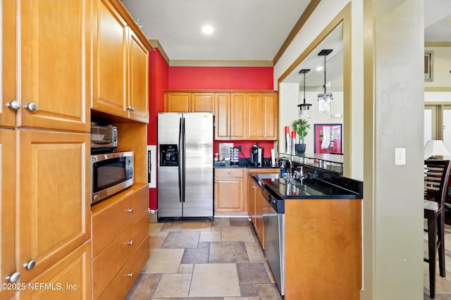 kitchen with brown cabinets, a sink, stone finish floor, dark stone countertops, and stainless steel appliances