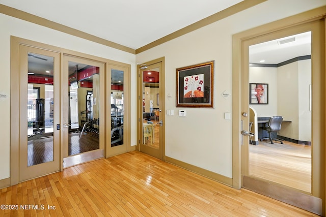 interior space featuring french doors, light wood-style flooring, baseboards, visible vents, and ornamental molding