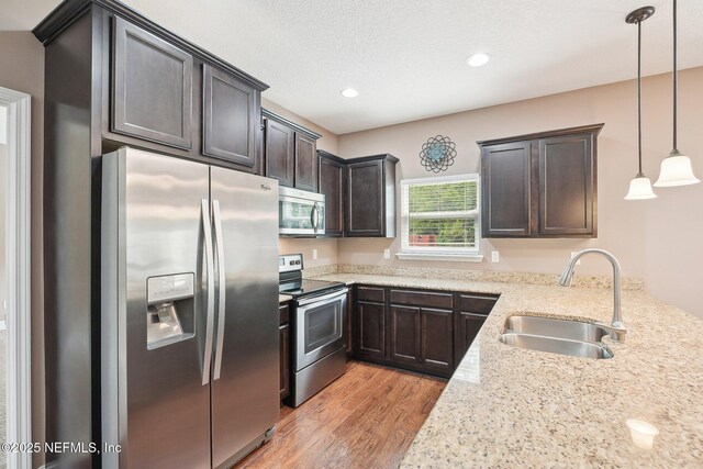 2968 Ravine Hill Dr, Middleburg, FL 32068 - kitchen with stainless steel appliances, a sink, light wood finished floors, dark brown cabinetry, and decorative light fixtures