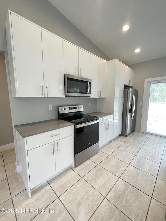 kitchen featuring stainless steel appliances, vaulted ceiling, and white cabinetry