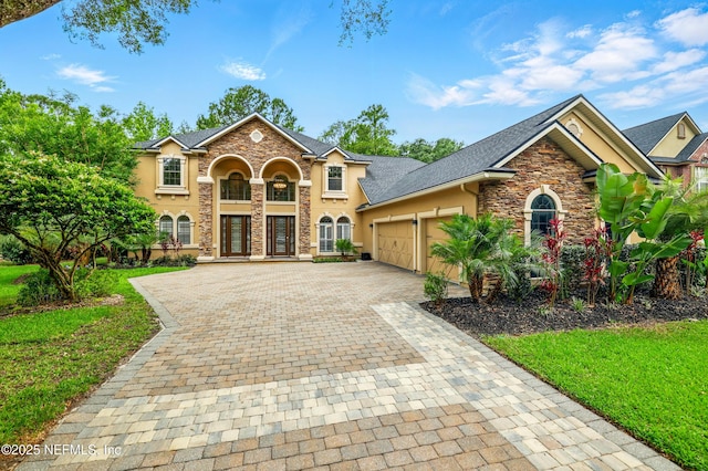 725 Carthage Pl, Saint Johns, FL 32259 - view of front of house with stone siding, decorative driveway, stucco siding, an attached garage, and a front yard