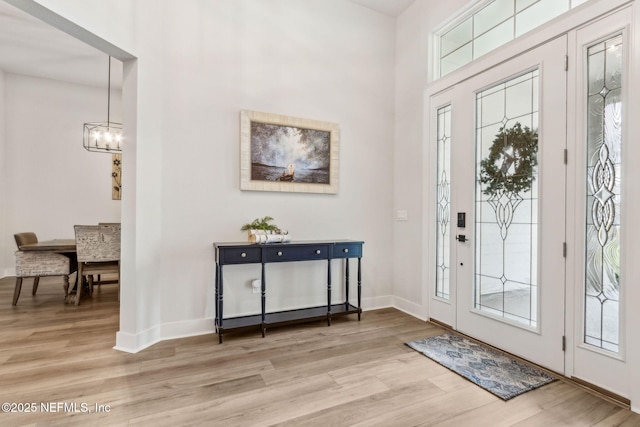 36039 Pitch Ln, Hilliard, FL 32046 - foyer entrance featuring light wood-type flooring, a chandelier, baseboards, and a high ceiling