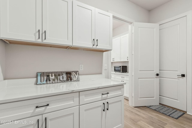 36039 Pitch Ln, Hilliard, FL 32046 - kitchen with light wood finished floors, white cabinets, light stone counters, and decorative backsplash