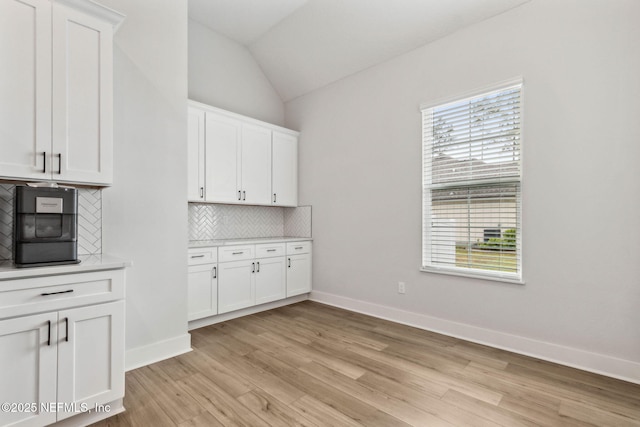 36039 Pitch Ln, Hilliard, FL 32046 - kitchen featuring backsplash, light wood-type flooring, light countertops, white cabinets, and lofted ceiling