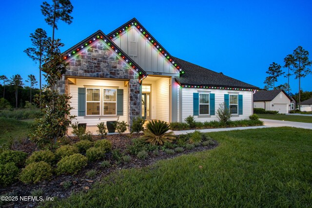 36039 Pitch Ln, Hilliard, FL 32046 - view of front facade featuring board and batten siding, a front yard, and stone siding