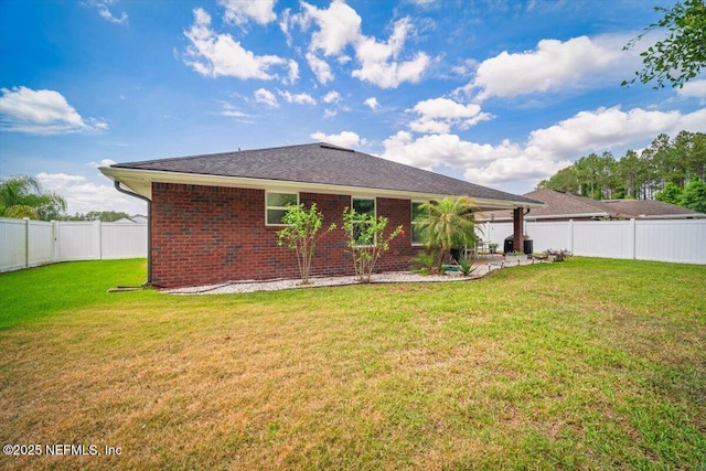 rear view of property with a lawn, brick siding, a fenced backyard, and a patio area