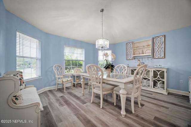 dining room featuring baseboards, an inviting chandelier, wood finished floors, and vaulted ceiling