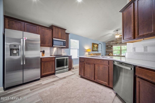 kitchen with ceiling fan, appliances with stainless steel finishes, light wood-type flooring, a sink, and lofted ceiling