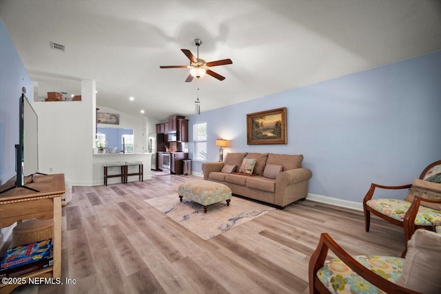living room with baseboards, a ceiling fan, light wood finished floors, and lofted ceiling