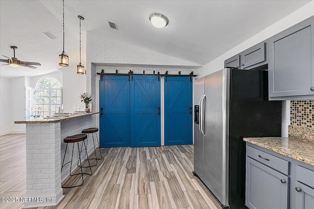 12322 Mastin Cove Rd, Jacksonville, FL 32225 - kitchen with lofted ceiling, stainless steel fridge with ice dispenser, gray cabinets, ceiling fan, and tasteful backsplash