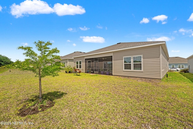 rear view of house featuring a lawn and a sunroom