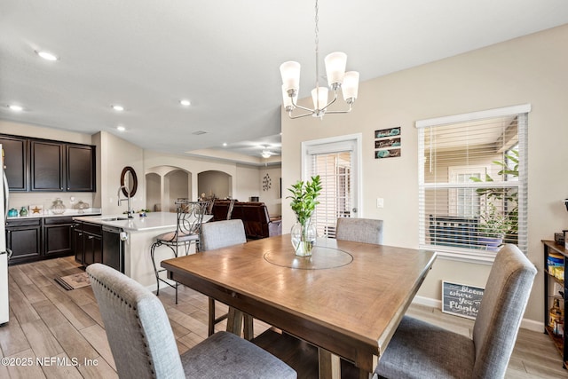 dining room with recessed lighting, arched walkways, light wood-style flooring, and a notable chandelier