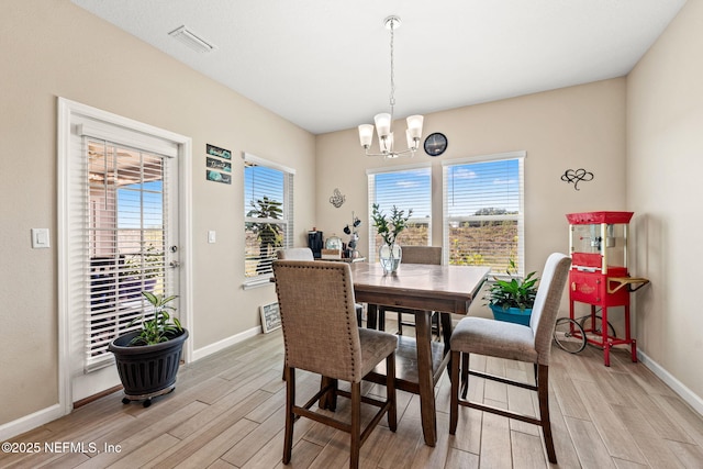 dining area with baseboards, a notable chandelier, visible vents, and light wood-style flooring