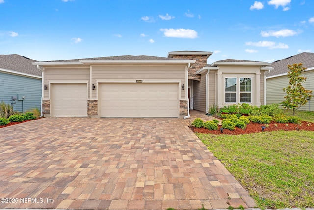 prairie-style home featuring a garage, decorative driveway, a front lawn, and stone siding