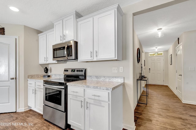 2471 Cold Stream Ln, Green Cove Springs, FL 32043 - kitchen featuring appliances with stainless steel finishes, light countertops, light wood-type flooring, white cabinets, and a textured ceiling
