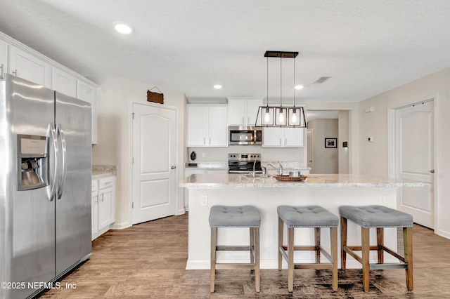 2471 Cold Stream Ln, Green Cove Springs, FL 32043 - kitchen with appliances with stainless steel finishes, white cabinets, light wood-style floors, a breakfast bar, and recessed lighting