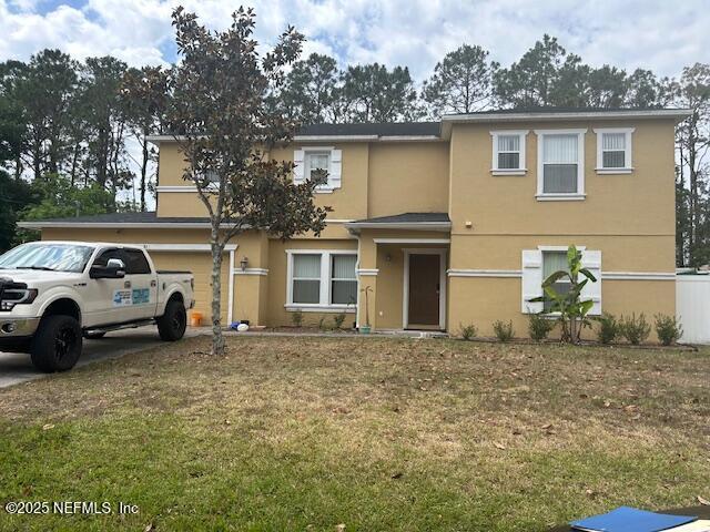 view of front of house with concrete driveway, stucco siding, and a front lawn