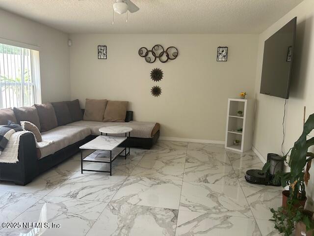 living room featuring ceiling fan, a textured ceiling, baseboards, and marble finish floor