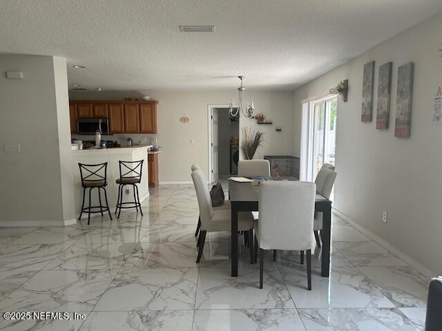 dining area featuring a textured ceiling, baseboards, marble finish floor, and visible vents
