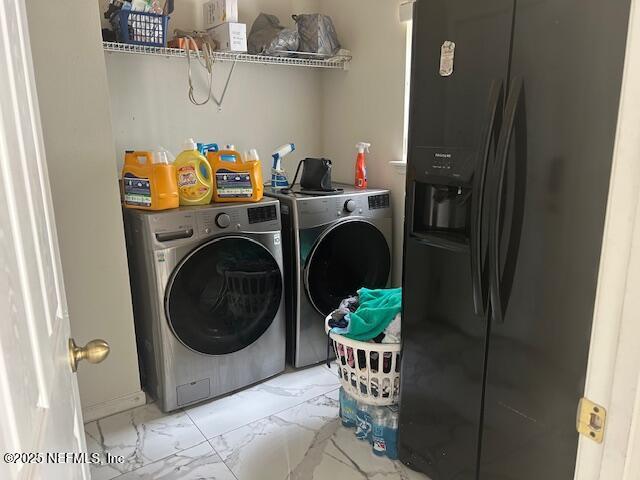 clothes washing area with washing machine and clothes dryer, marble finish floor, and laundry area