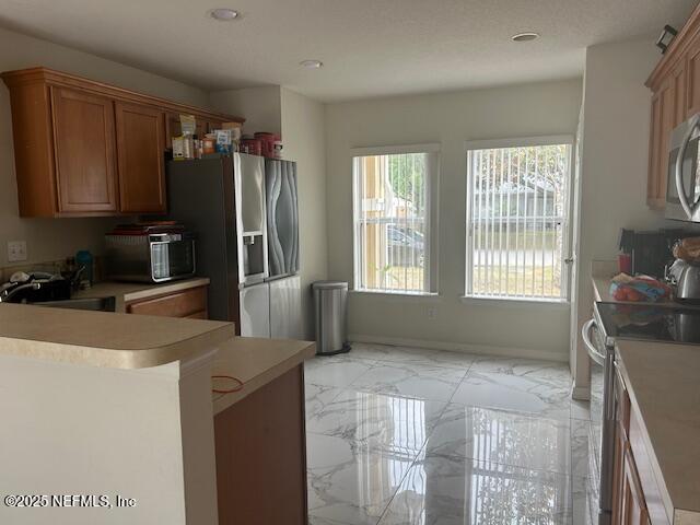 kitchen with recessed lighting, marble finish floor, a sink, light countertops, and appliances with stainless steel finishes