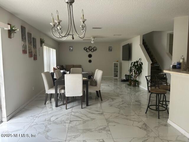 dining room featuring baseboards, stairway, an inviting chandelier, and a textured ceiling