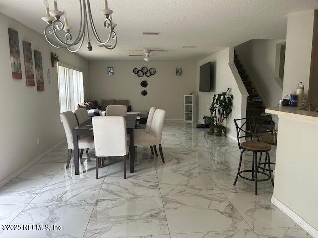 dining space featuring baseboards, marble finish floor, stairway, and ceiling fan with notable chandelier