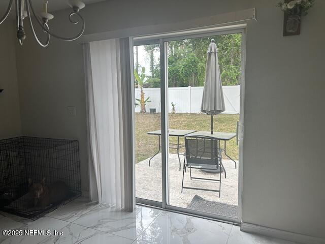 doorway to outside with marble finish floor and a chandelier