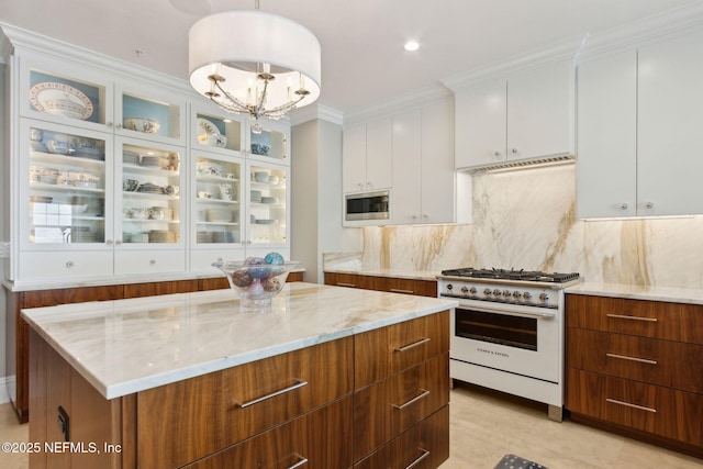 kitchen featuring range with gas stovetop, stainless steel microwave, white cabinetry, light stone countertops, and tasteful backsplash