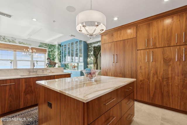 kitchen featuring a sink, a chandelier, a kitchen island, and brown cabinets
