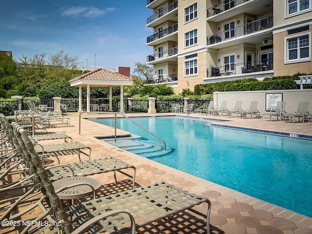 community pool with a gazebo, fence, and a patio area