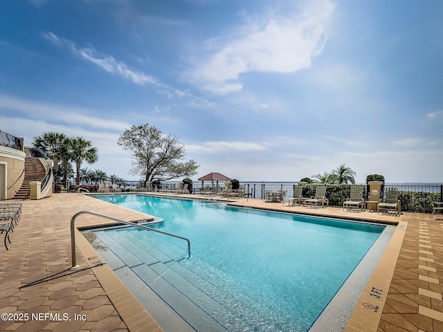 community pool featuring fence, a patio area, and stairs