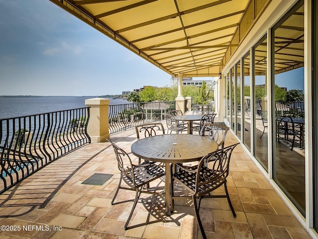 balcony with a water view and outdoor dining area