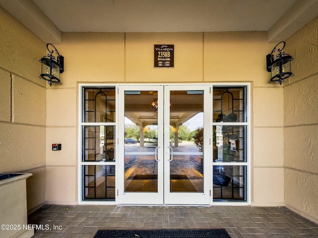 view of exterior entry with french doors and stucco siding