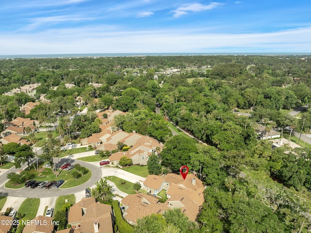 view of property location with nearby suburban area and a forest