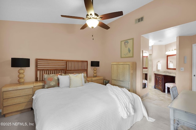 bedroom featuring lofted ceiling, connected bathroom, light colored carpet, and a ceiling fan