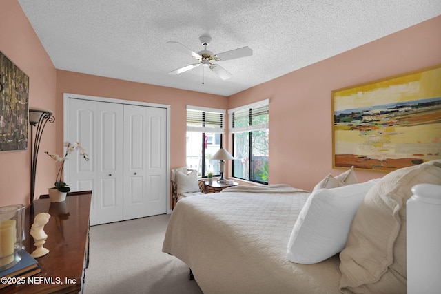bedroom featuring light carpet, a closet, a textured ceiling, and a ceiling fan