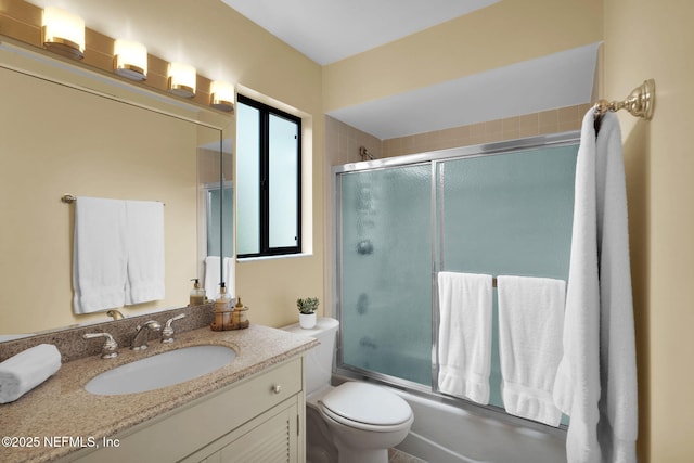 bathroom with combined bath / shower with glass door, vanity, and toilet