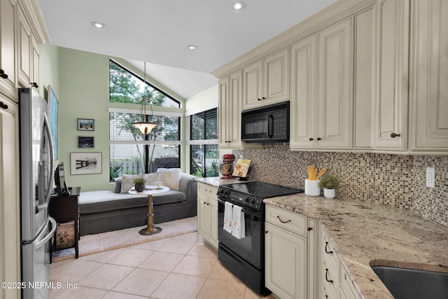 kitchen with black appliances, cream cabinets, tasteful backsplash, vaulted ceiling, and light tile patterned flooring