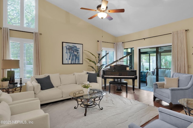 living area with healthy amount of natural light, a ceiling fan, wood finished floors, and high vaulted ceiling