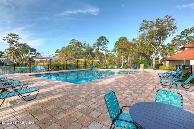 community pool with fence and a patio area