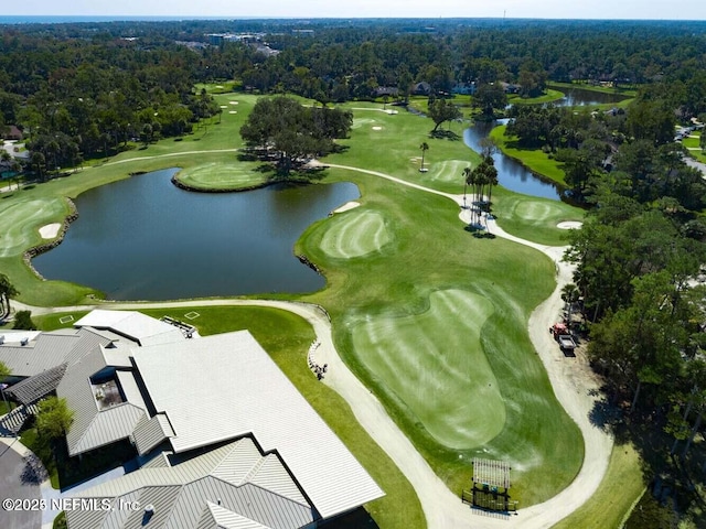drone / aerial view of a large body of water, a golf course, and a forest