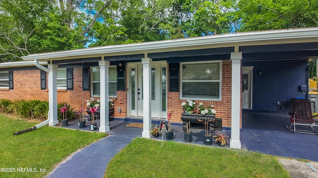 3165 Victoria Park Rd, Jacksonville, FL 32216 - view of front facade with a porch, brick siding, a front yard, and an attached carport