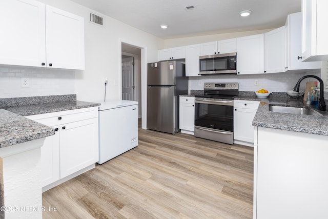 3165 Victoria Park Rd, Jacksonville, FL 32216 - kitchen featuring white cabinets, appliances with stainless steel finishes, a sink, light wood-type flooring, and visible vents
